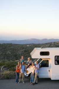 Multi-generation family relaxing in countryside on motor home vacation